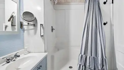 a white bathroom with a shower curtain and a sink at Delmar Dunes by Sand Seeker Vacations in Panama City Beach