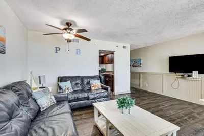 a living room with a couch and a tv at Beachfront Panama City Condo with Balcony and Views! in Panama City Beach
