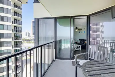 a balcony with a chair and a view of a building at Beachfront Panama City Condo with Balcony and Views! in Panama City Beach