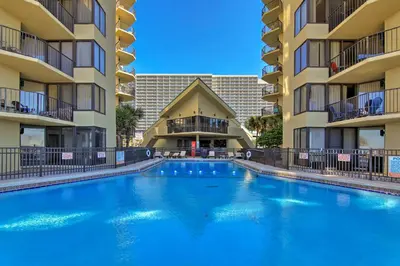a large swimming pool in front of two apartment buildings at Beachfront Panama City Condo with Balcony and Views! in Panama City Beach