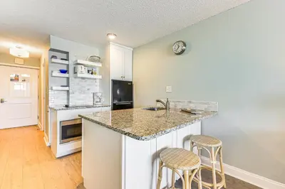 a kitchen with a sink and two stools at PCB Coastal Condo with On-Site Beach Access! in Panama City Beach