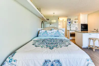 a bedroom with a large bed with blue and white pillows at PCB Coastal Condo with On-Site Beach Access! in Panama City Beach