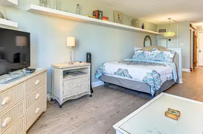 a bedroom with a bed and a dresser with a lamp at PCB Coastal Condo with On-Site Beach Access! in Panama City Beach