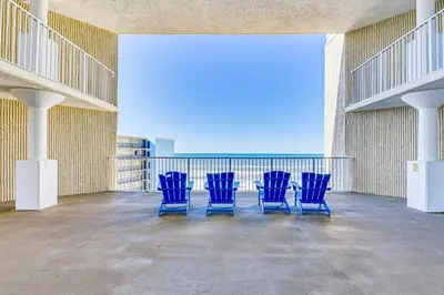 four blue chairs in a large room with a balcony at PCB Coastal Condo with On-Site Beach Access! in Panama City Beach