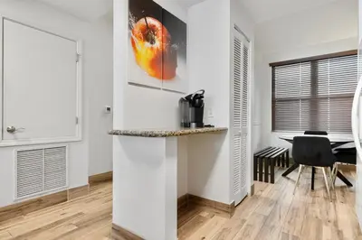 a living room with white walls and a table with a chair at AQUA RESORT! Beachfront, 3 Bedroom Condo! 2 Bedrooms Beach Front! Sleeps 7! Free Beach Chairs by Dolce Vita Getaways PCB in Panama City Beach