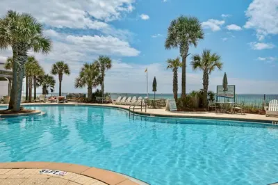 a large swimming pool with palm trees and the ocean at AQUA RESORT! Beachfront, 3 Bedroom Condo! 2 Bedrooms Beach Front! Sleeps 7! Free Beach Chairs by Dolce Vita Getaways PCB in Panama City Beach