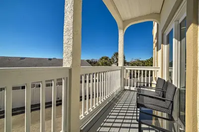 a balcony with two chairs on a house at Sunny PCB Home with Balcony Steps to the Beach! in Panama City Beach