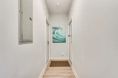 a hallway with white walls and a painting on the wall at Renovated PCB Studio, 2 Min Walk To Laguna Beach! in Panama City Beach