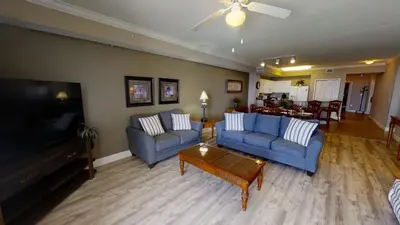 a living room with two blue couches and a tv at Tidewater 1102 in Panama City Beach