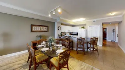 a dining room and kitchen with a table and chairs at Tidewater 1102 in Panama City Beach