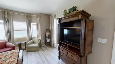 a living room with a flat screen tv in a cabinet at Tidewater 1102 in Panama City Beach