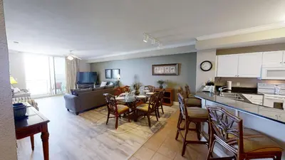 a kitchen and living room with a table and chairs at Tidewater 1102 in Panama City Beach