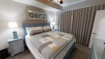 a bedroom with a large bed and a nightstand with a bed sidx sidx sidx at Tidewater 704 in Panama City Beach
