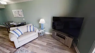 a living room with a couch and a flat screen tv at Tidewater 704 in Panama City Beach
