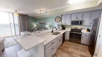 a kitchen with white appliances and a large window at Tidewater 704 in Panama City Beach