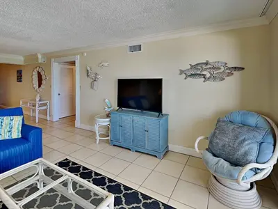 a living room with a blue couch and a tv at Regency Towers 505 in Panama City Beach