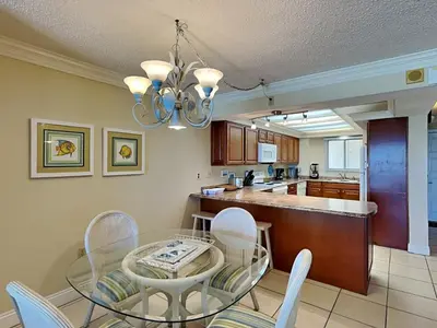 a dining room and kitchen with a glass table and chairs at Regency Towers 505 in Panama City Beach