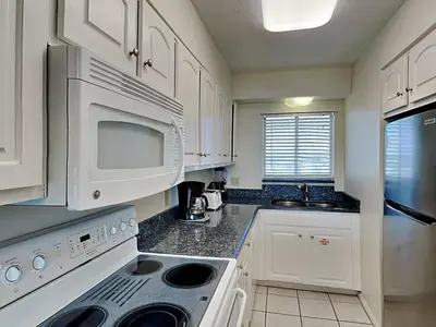 a kitchen with white cabinets and a white microwave at Regency Towers Panama City Beach #719 in Panama City Beach