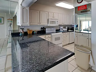 a kitchen with white cabinets and a black counter top at Regency Towers Panama City Beach #719 in Panama City Beach
