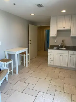 a kitchen with white cabinets and a table and a sink at Sterling Breeze 1007 in Panama City Beach