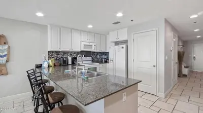 a kitchen with white cabinets and a marble counter top at Sterling Breeze 1007 in Panama City Beach