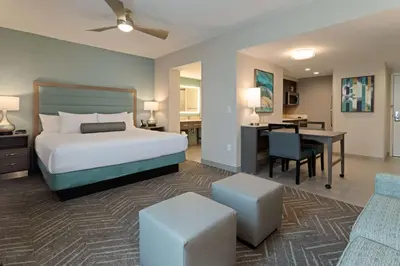 a bedroom with a bed and a desk and a table at Homewood Suites By Hilton Panama City Beach, Fl in Panama City Beach