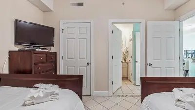 a bedroom with two beds and a flat screen tv at Ocean Villa 305 by Sand Seeker Vacations in Panama City Beach