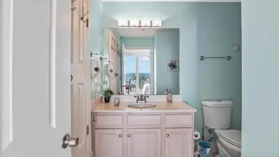 a bathroom with a sink and a toilet and a mirror at Ocean Villa 305 by Sand Seeker Vacations in Panama City Beach