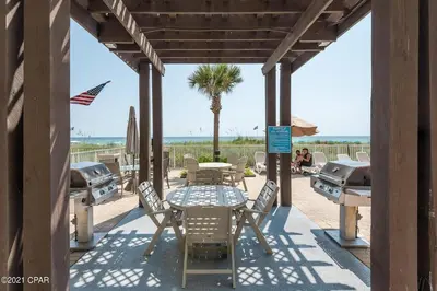 a patio with a table and chairs and a palm tree at Ocean Villa 305 by Sand Seeker Vacations in Panama City Beach
