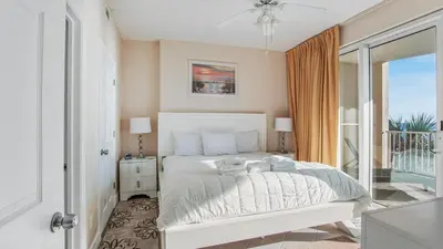 a bedroom with a white bed and a balcony at Ocean Villa 305 by Sand Seeker Vacations in Panama City Beach