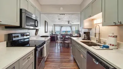 a kitchen with white cabinets and black appliances at The Shell Shack #3 by Sand Seeker Vacations in Panama City Beach