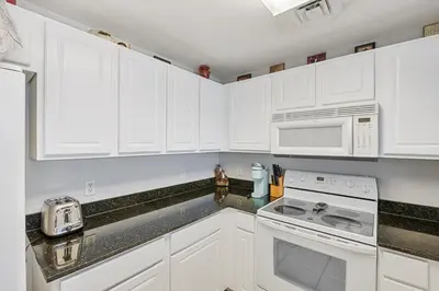 a kitchen with white cabinets and a stove and microwave at Calypso Resort Beachfront Condo in Panama City Beach