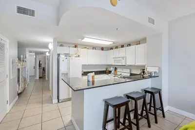 a kitchen with white cabinets and bar stools at Calypso Resort Beachfront Condo in Panama City Beach