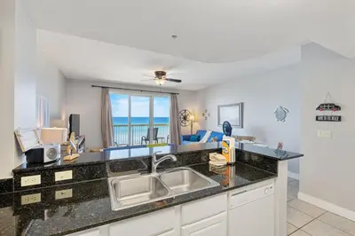 a kitchen with a sink and a view of the ocean at Calypso Resort Beachfront Condo in Panama City Beach