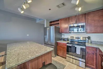 a kitchen with wooden cabinets and stainless steel appliances at Lagoon-View Balcony! Family Resort Escape in PCB in Panama City Beach