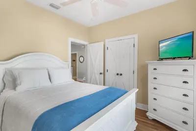 a bedroom with a white bed and a flat screen tv at Beach Bungalow, 3 Min Walk to Beach, Golf Cart, 4 bikes, Wagon in Seacrest