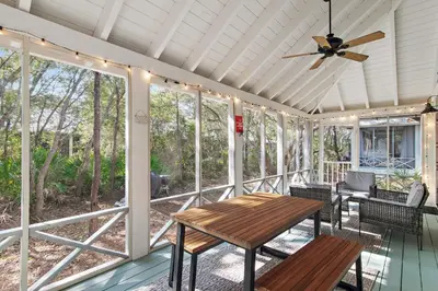 a screened porch with a wooden table and a ceiling fan at Beach Bungalow, 3 Min Walk to Beach, Golf Cart, 4 bikes, Wagon in Seacrest