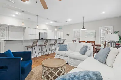 a living room with white furniture and a kitchen at Beach Bungalow, 3 Min Walk to Beach, Golf Cart, 4 bikes, Wagon in Seacrest