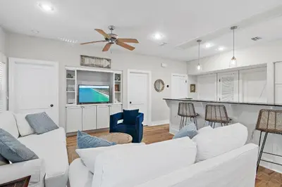 a living room with white furniture and a kitchen at Beach Bungalow, 3 Min Walk to Beach, Golf Cart, 4 bikes, Wagon in Seacrest