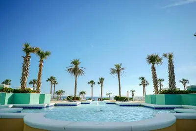 a pool with palm trees and a fountain at En Soleil #1522 West in Panama City Beach