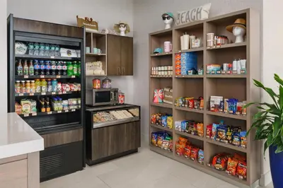 a kitchen with a refrigerator and shelves of food at Hyatt Place Panama City Beach - Beachfront in Panama City Beach