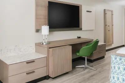 a hotel room with a desk with a tv and a green chair at Hyatt Place Panama City Beach - Beachfront in Panama City Beach