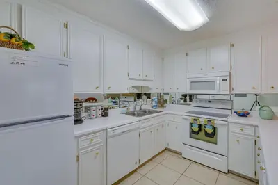 a white kitchen with white cabinets and white appliances at Cozy PCB Condo Less Than half Mile to Public Beach Access! in Panama City Beach