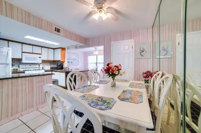 a kitchen with a table and chairs with flowers on it at Panama City Beach Townhome - Walk to Beach! in Panama City Beach