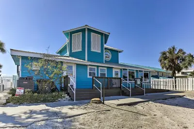 a blue house with a porch on a beach at Panama City Beach Townhome - Walk to Beach! in Panama City Beach