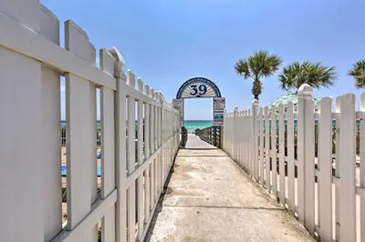 a fence with a clock at the beach at Panama City Beach Townhome - Walk to Beach! in Panama City Beach