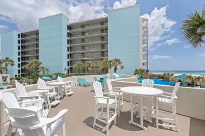 a row of white chairs and tables on the balcony of a resort at Top Of The Gulf 621 in Panama City Beach