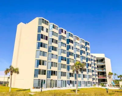a large white building with palm trees in front of it at Top of The Gulf 213 in Panama City Beach