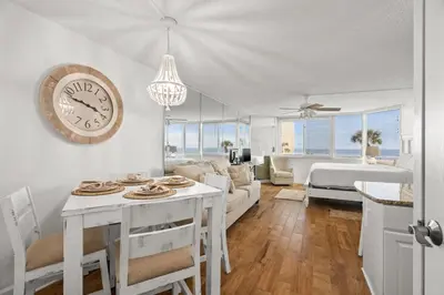 a living room with a table and a clock on the wall at Top of The Gulf 213 in Panama City Beach