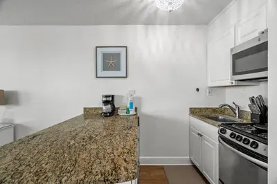 a kitchen with white cabinets and a granite counter top at Top of The Gulf 213 in Panama City Beach